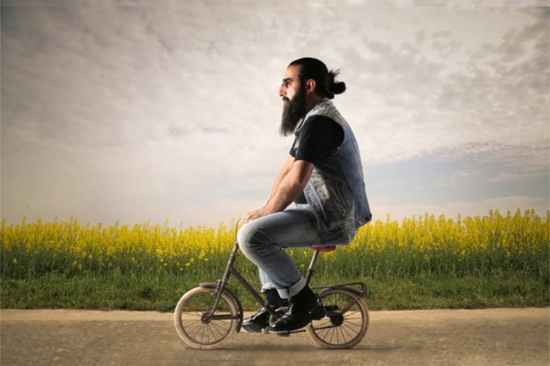 short cycling -- Bearded man is sitting on a small bicycle