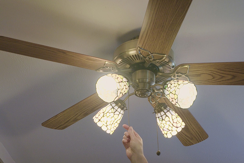 someone turning on their ceiling fan to save energy and not using their AC