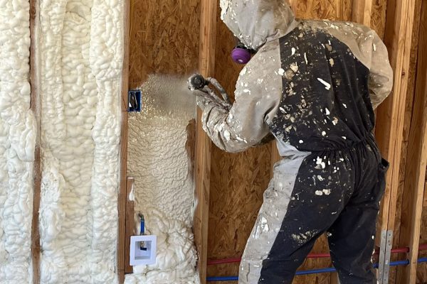 Worker in Phoenix, AZ wearing personal protective equipment (PPE) spray foam insulation on a job site.